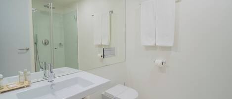A modern bathroom with a white sink, mirror, and toilet.