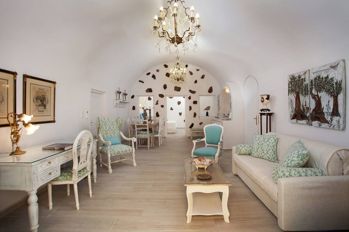 Amplia sala de estar con candelabro, sofá, sillones y una mesa de centro.