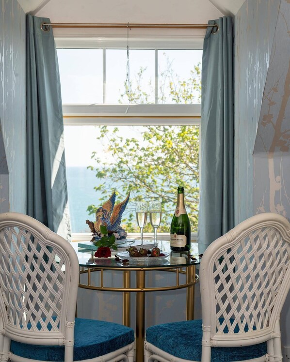 A room with a table set for two, featuring a bottle of wine, two glasses, and a decorative bird statue.