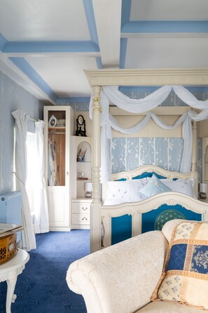 Une chambre à coucher avec un lit à baldaquin, une coiffeuse avec un miroir et un dressing.