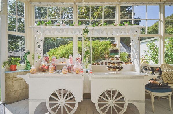 A white outdoor kiosk with two large wheels, surrounded by greenery and a clear view of the sky. - Enchanted Manor (Ventnor)