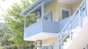 A two-story building with a balcony, a staircase, and a door. - Nerina Studios (Lefkada)