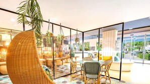 Een modern interieur met een ronde tafel, rieten stoelen en een hangplant.