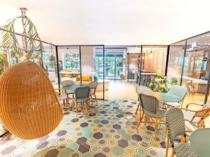 A modern interior with hexagonal patterned flooring, wicker furniture, and glass partitions.