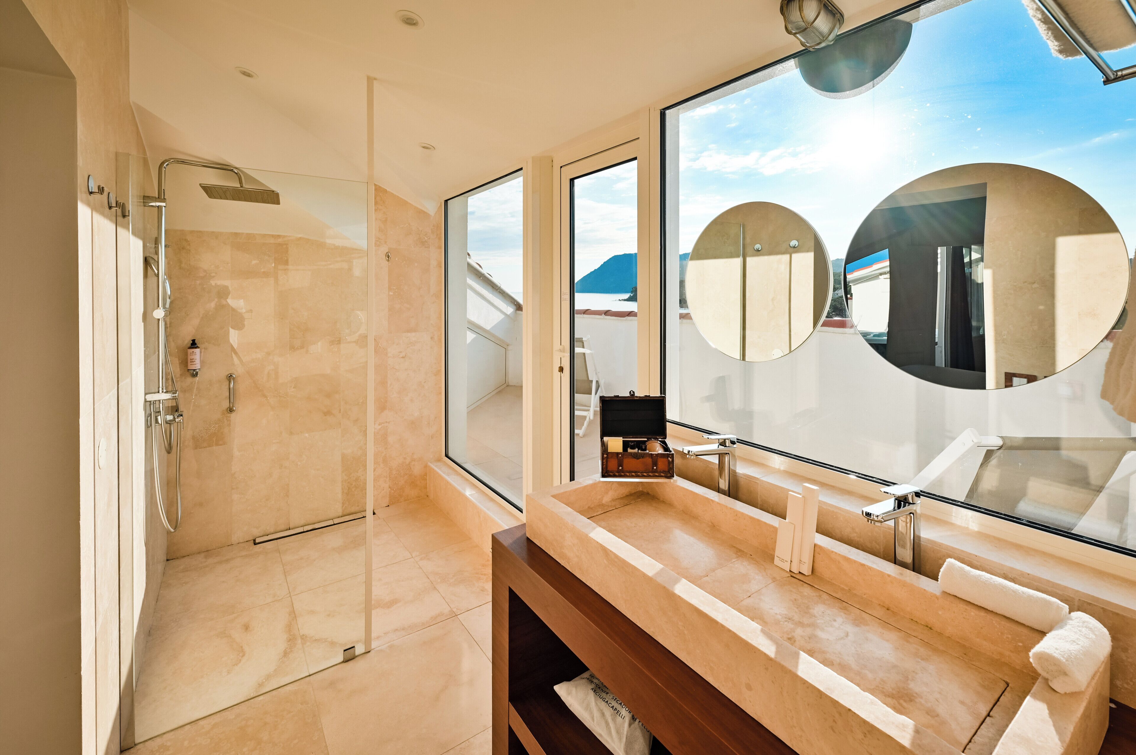 A modern bathroom with a glass-enclosed shower, a large mirror, and a vanity with a sink.