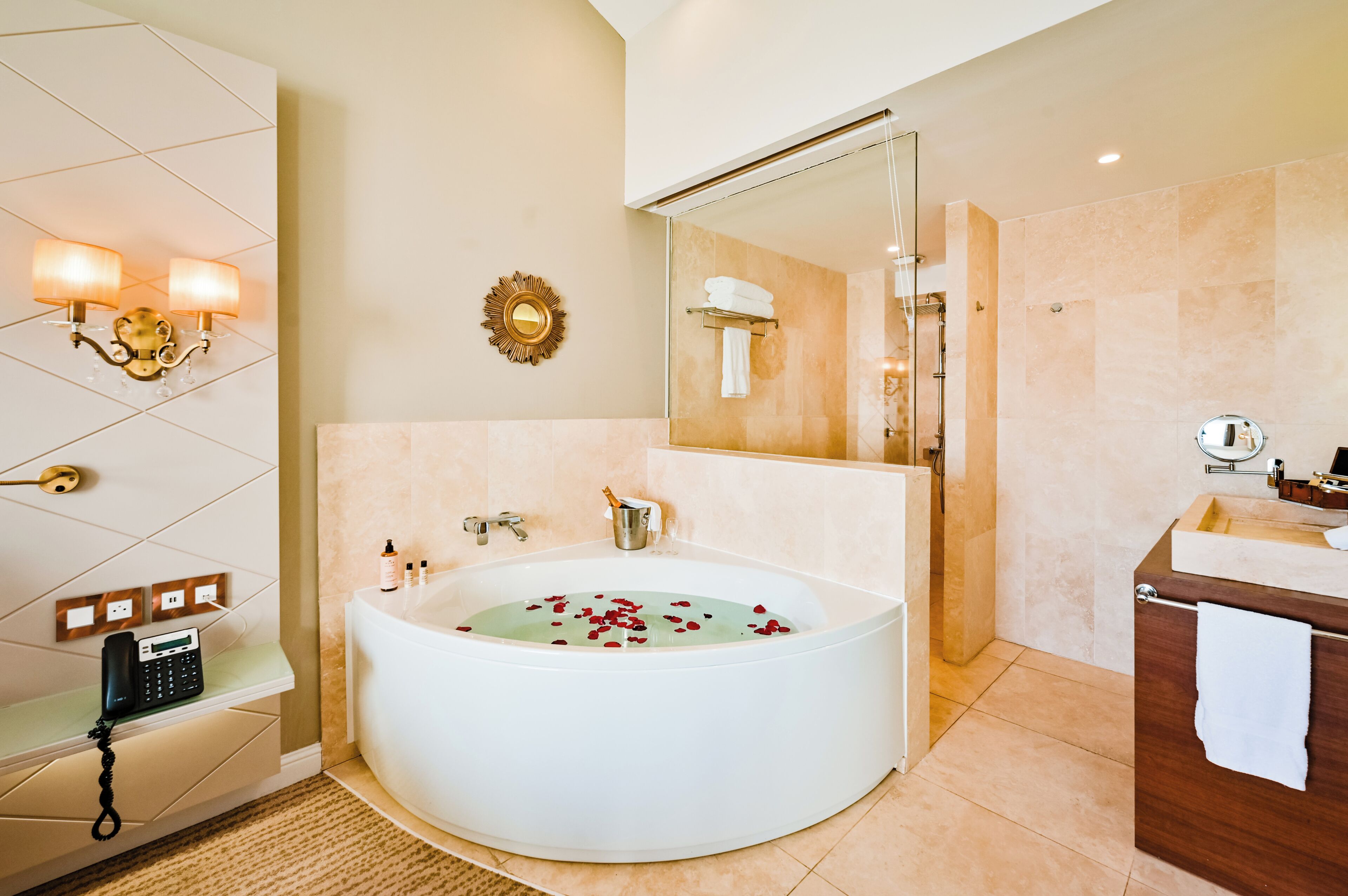 A modern bathroom with a large bathtub, a vanity with a mirror, and a wall-mounted phone.