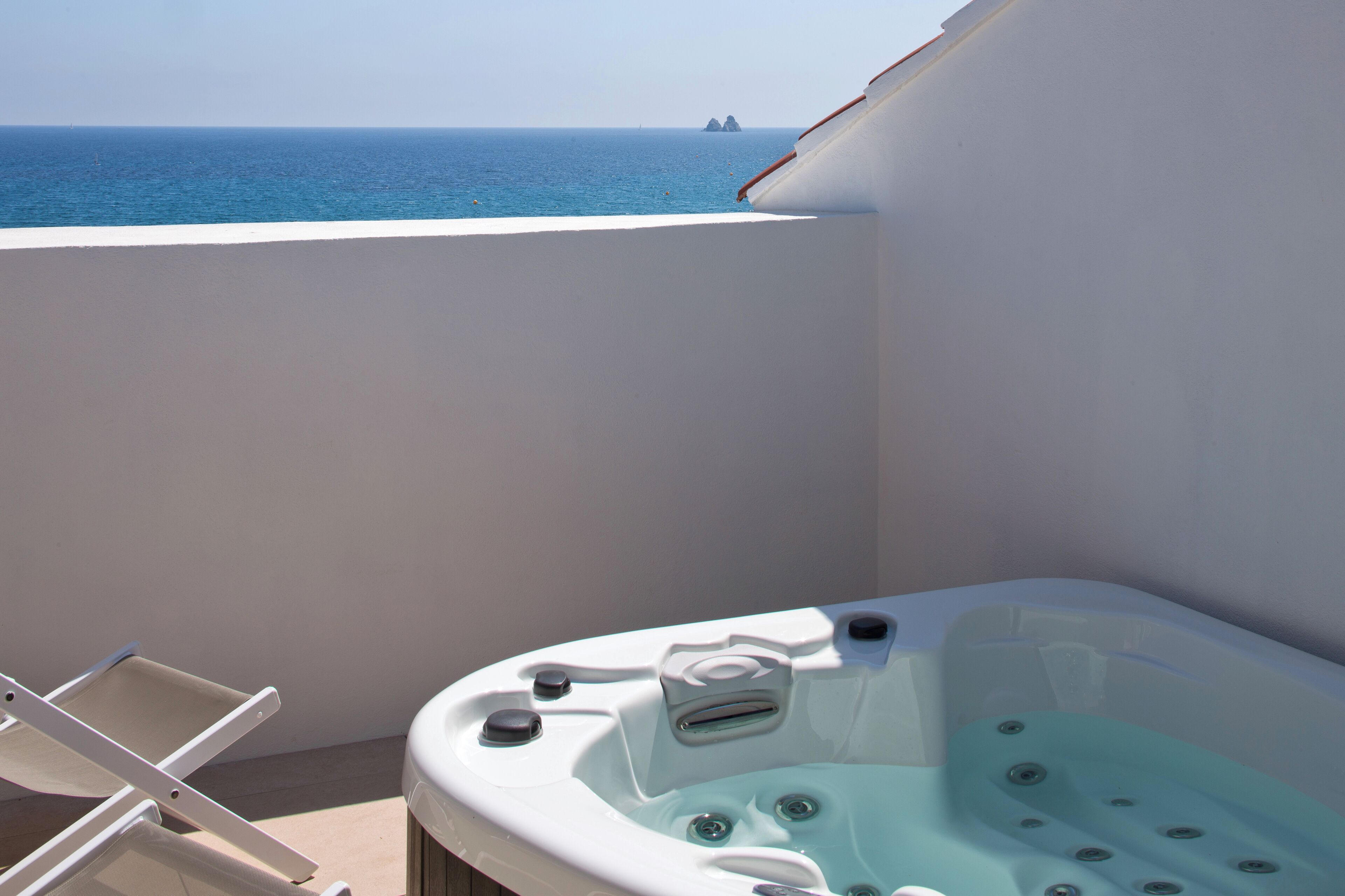 A balcony with a hot tub and a view of the ocean.