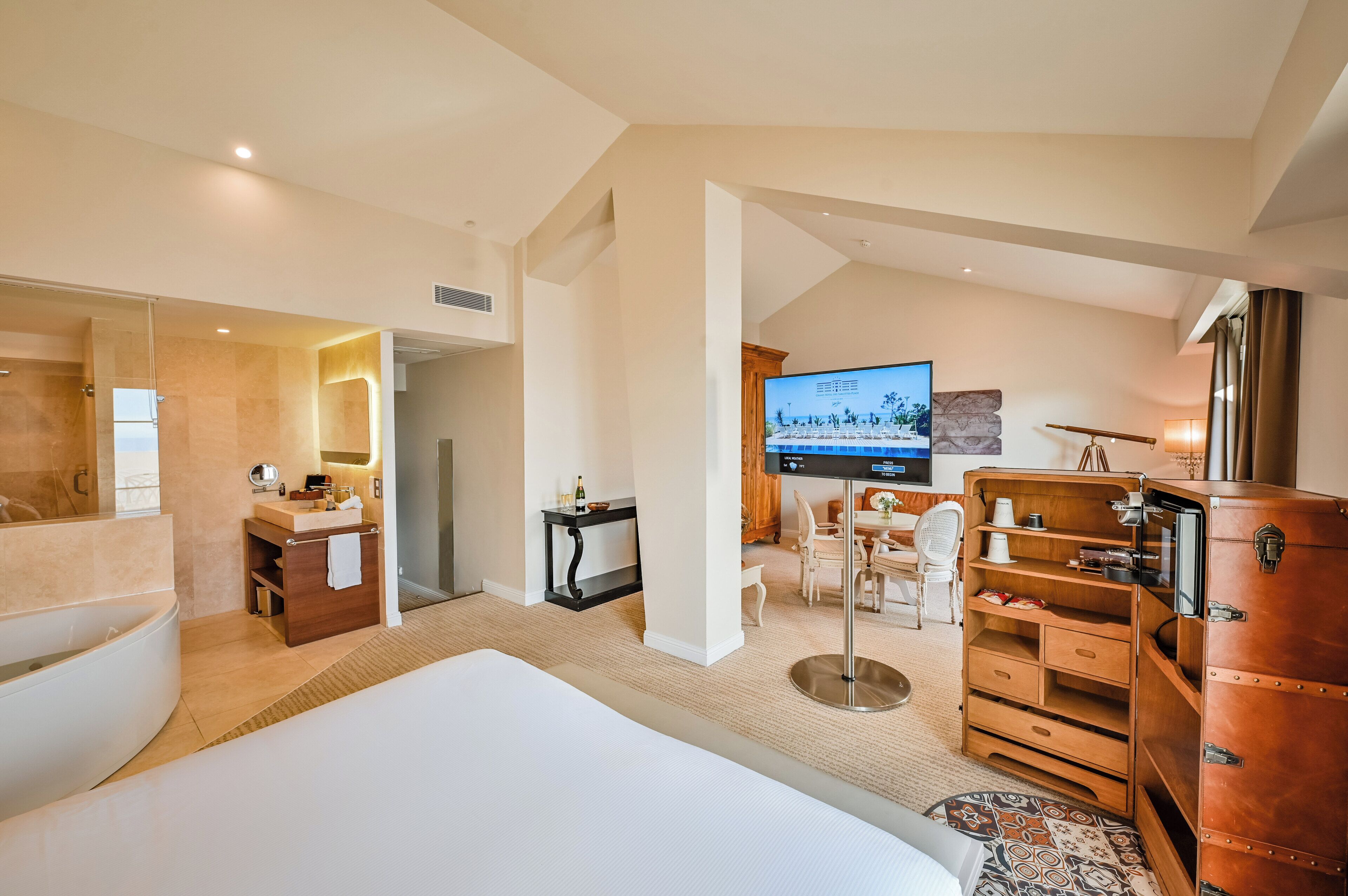 Ein Hotelzimmer mit einem großen Bett, einem Fernseher, einer Holzkommode, einem Schreibtisch und einem Stuhl.