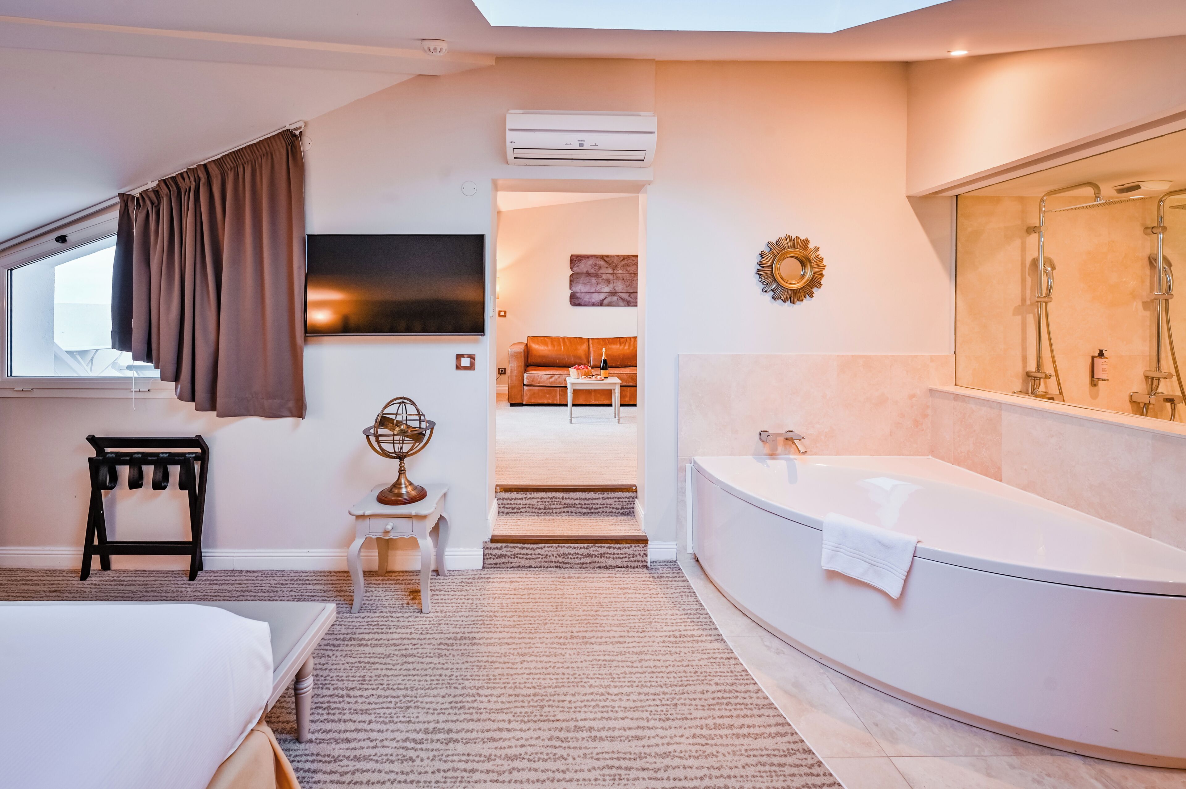 A modern bathroom with a large bathtub, a shower area, and a flat-screen TV mounted on the wall.