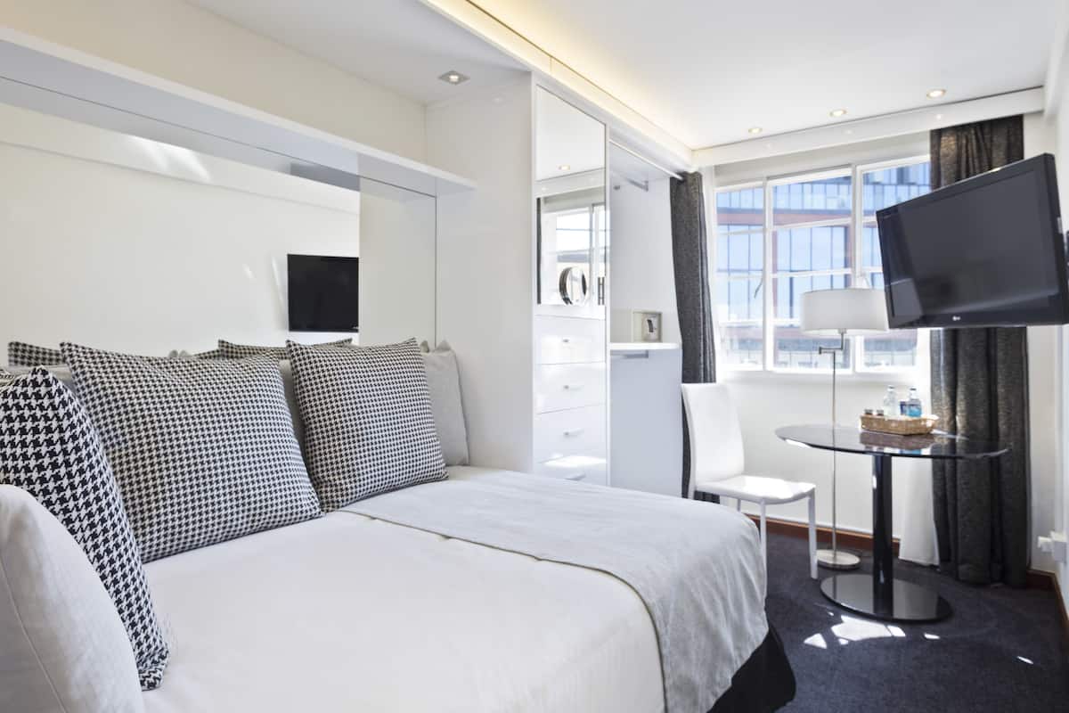 Une chambre d’hôtel moderne équipée d’un grand lit, d’un téléviseur à écran plat, d’une petite table et d’une chaise.