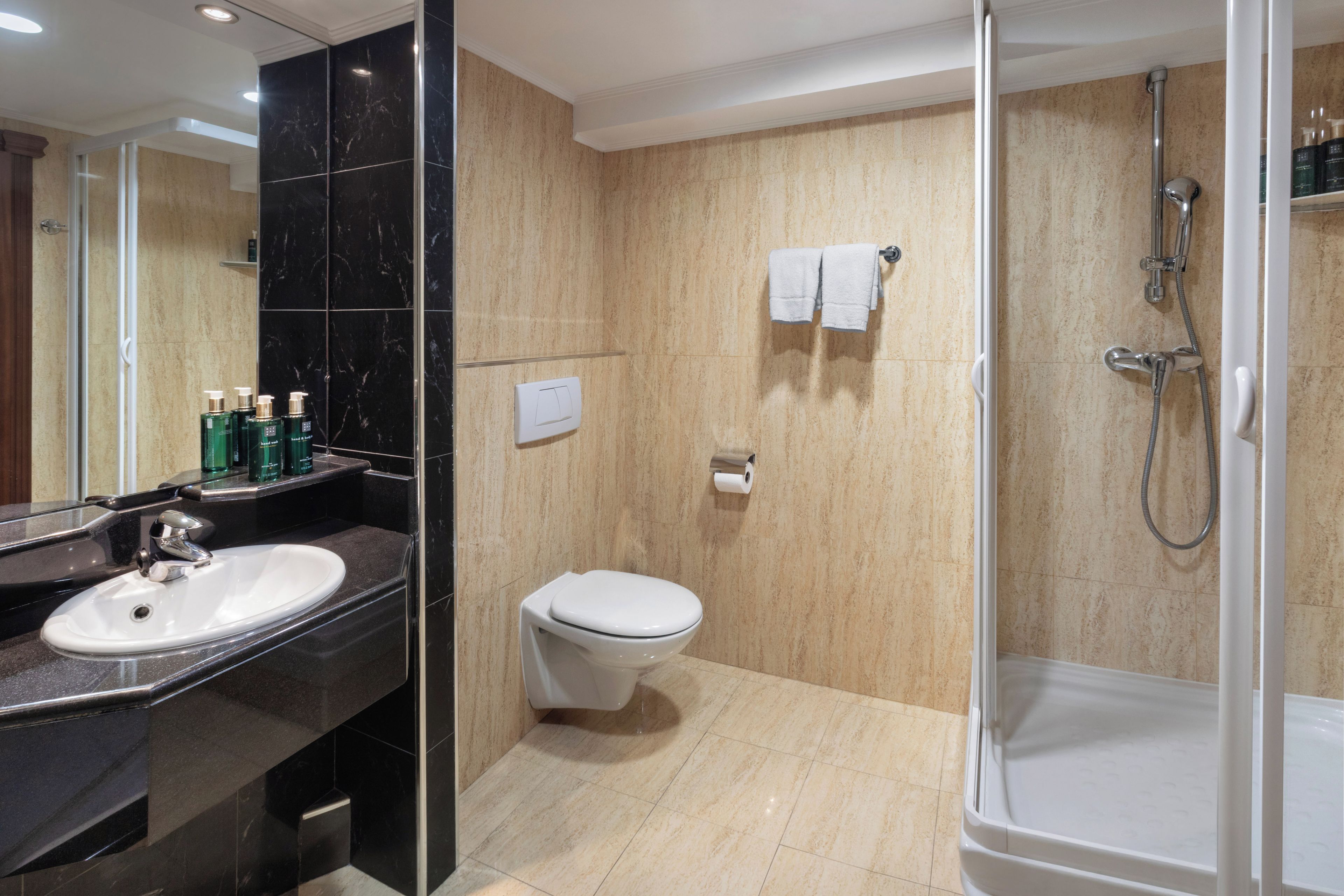 Une salle de bain moderne avec une douche à parois de verre, des toilettes blanches et un meuble-lavabo avec un évier et des articles de toilette.