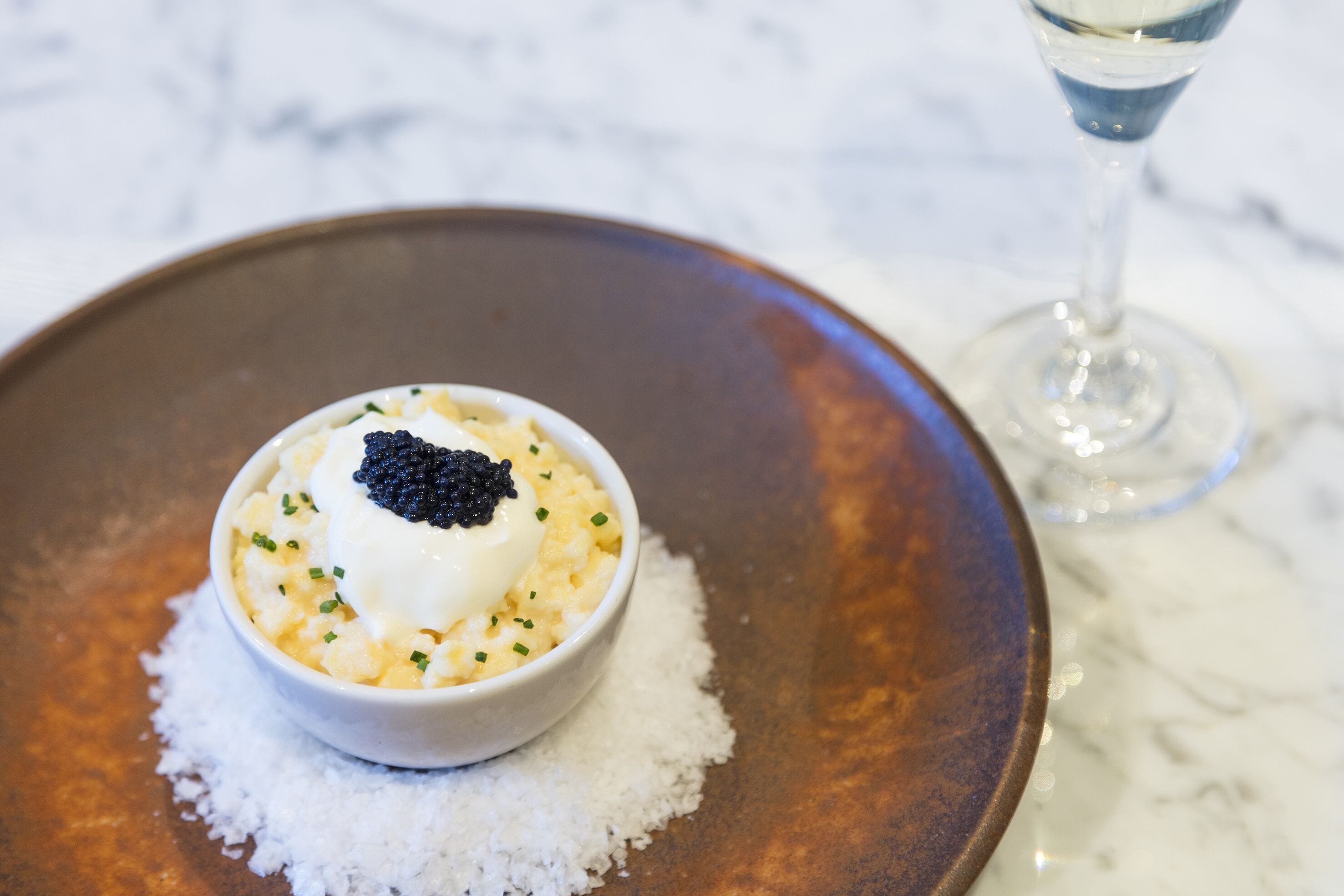 A bowl of food on a plate with a glass of water nearby.