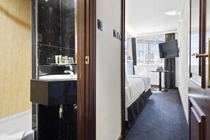 A hotel room with a marble bathroom, a bed, a TV, and a window. - Melia White House Apartments (London)