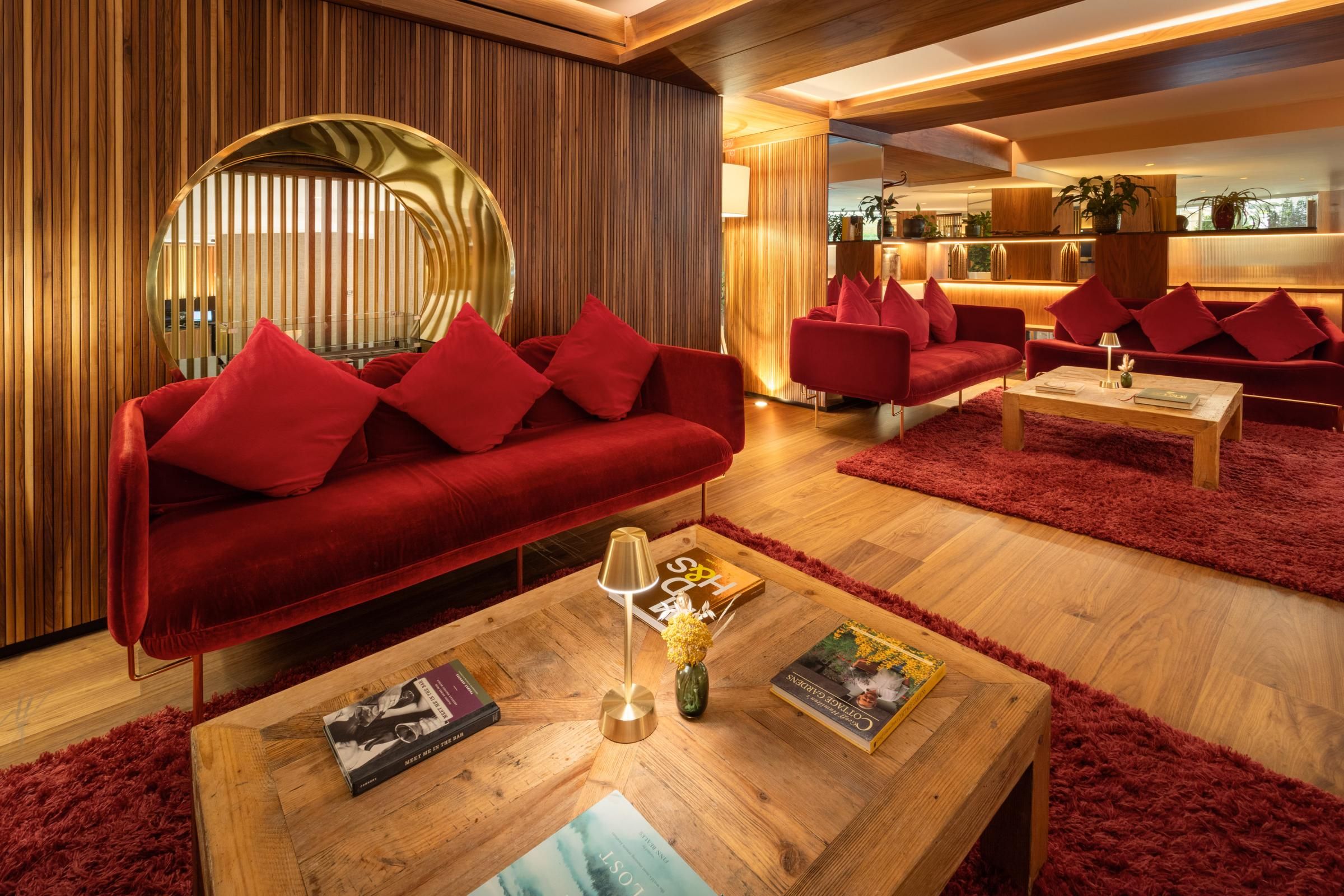 Un área de estar moderna con sofás rojos, una mesa de centro de madera y un espejo grande.