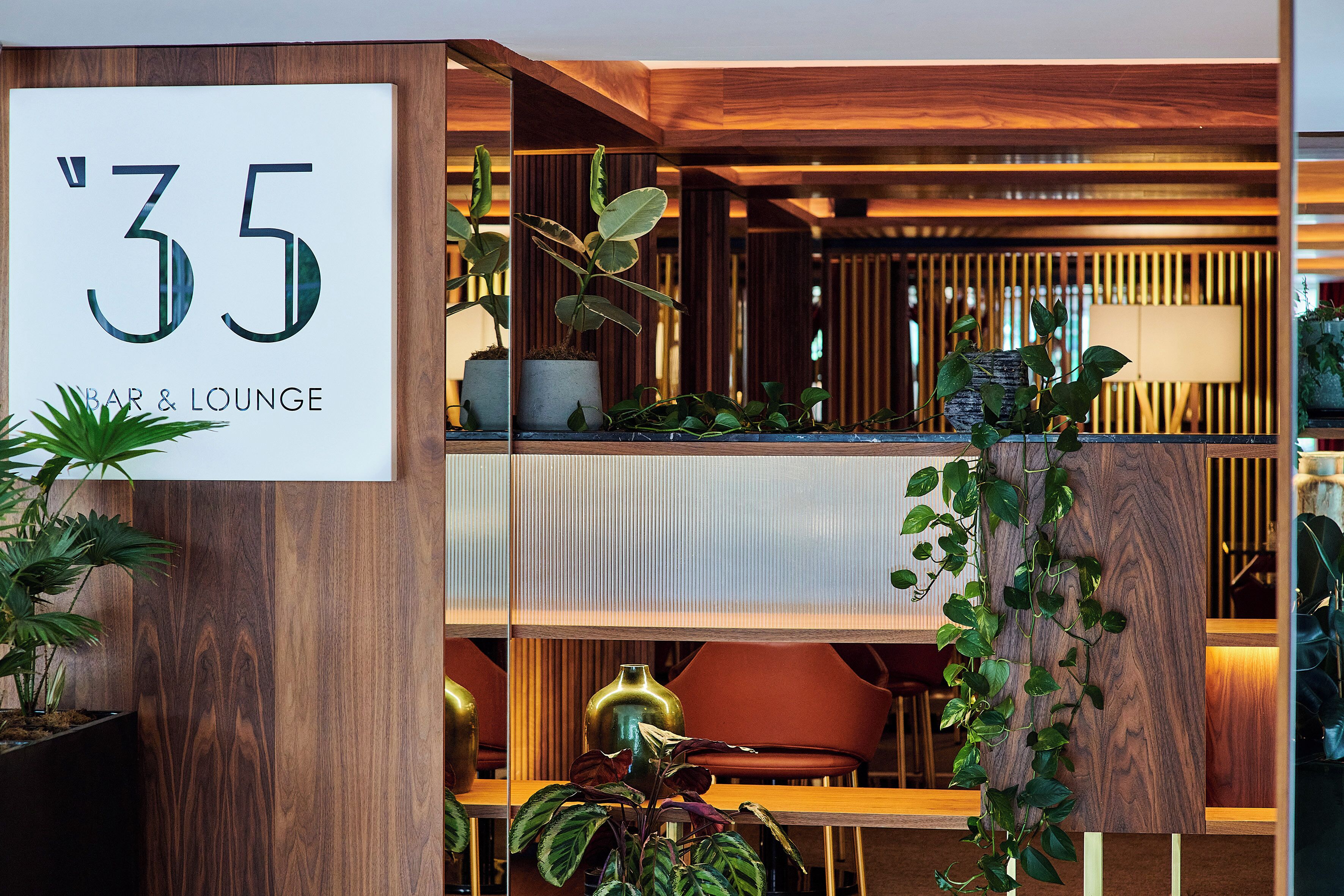 A '35 Bar & Lounge' sign, wooden paneling, and indoor plants.