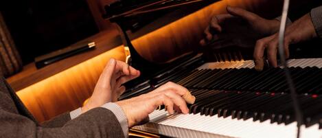 A person playing a grand piano in a room with wooden paneling and a warm ambiance.