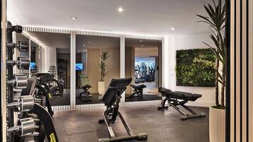 A modern gym with exercise equipment, a large mirror, and a green wall with plants.