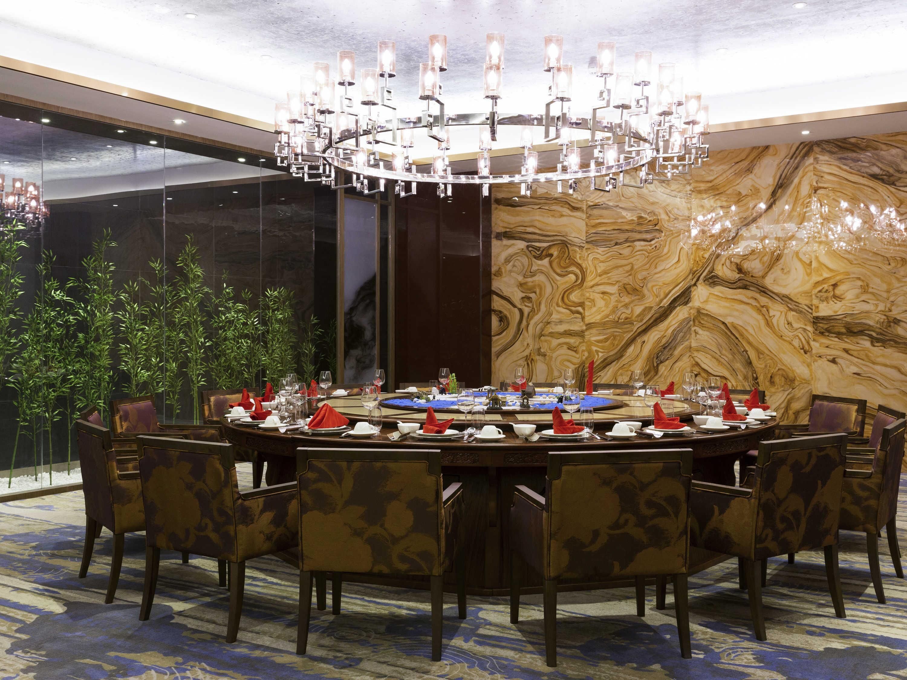 A formal dining room with a large chandelier, round table, and chairs.