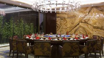A formal dining room with a large chandelier, round table, and chairs.