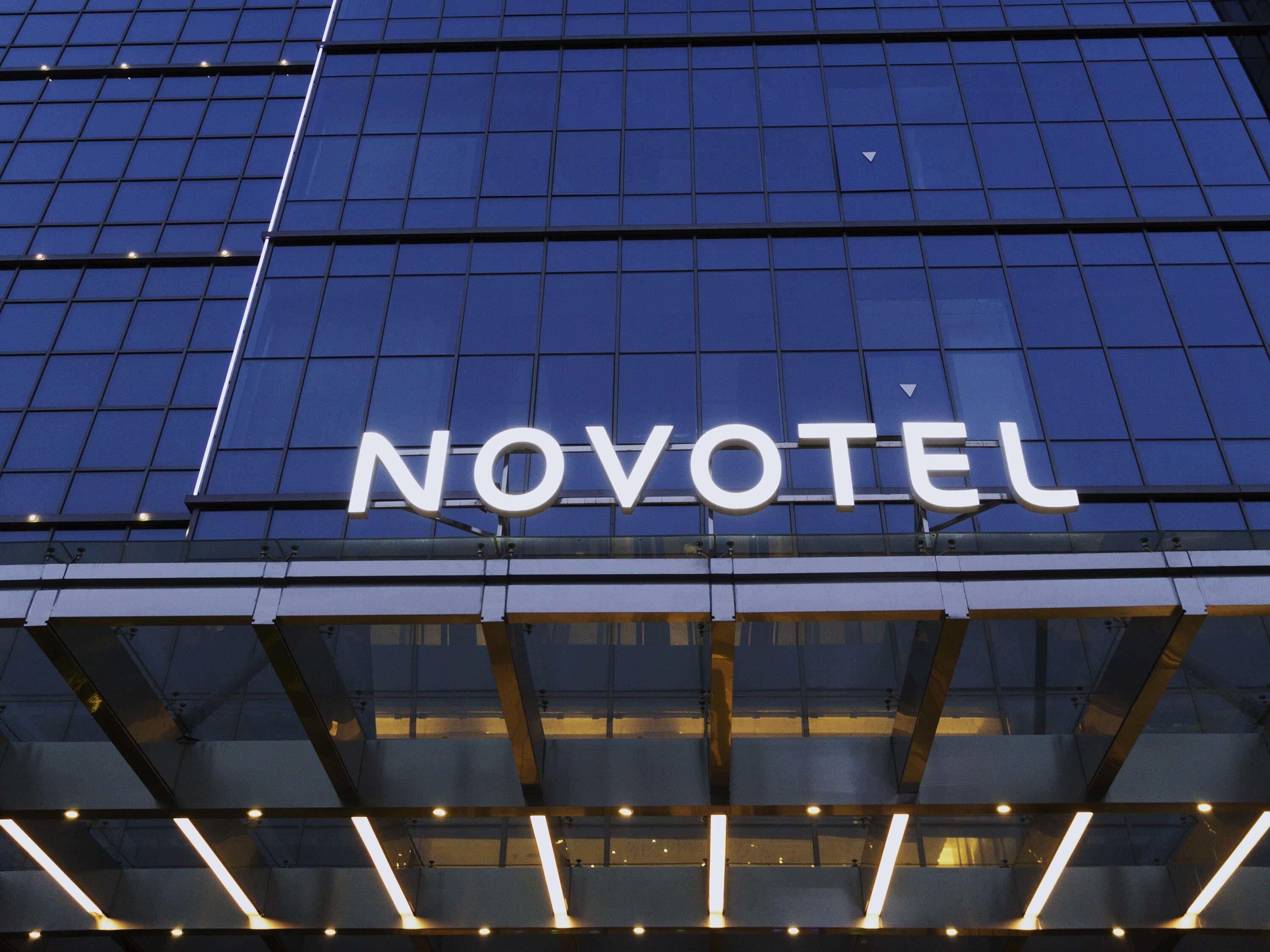 A modern building with a glass facade and the word 'NOVOTEL' prominently displayed.