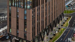 A modern hotel with a prominent 'NOVOTEL' sign, featuring a sleek, contemporary design with large windows and a structured facade.