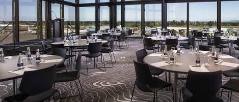 A conference room with round tables, chairs, and a carpeted floor.
