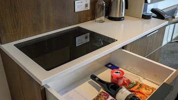 A hotel room with a minibar, a coffee maker, a kettle, and a bottle of wine.