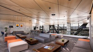 A modern lounge area with sofas, tables, and a view of a cityscape.