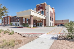 A Comfort Suites hotel with a covered entrance, parking lot, and a clear sky. - Comfort Suites Kyle (Kyle)