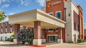 A Comfort Suites hotel with a brick facade, a covered entrance, and a clear sky. - Comfort Suites Kyle (Kyle)