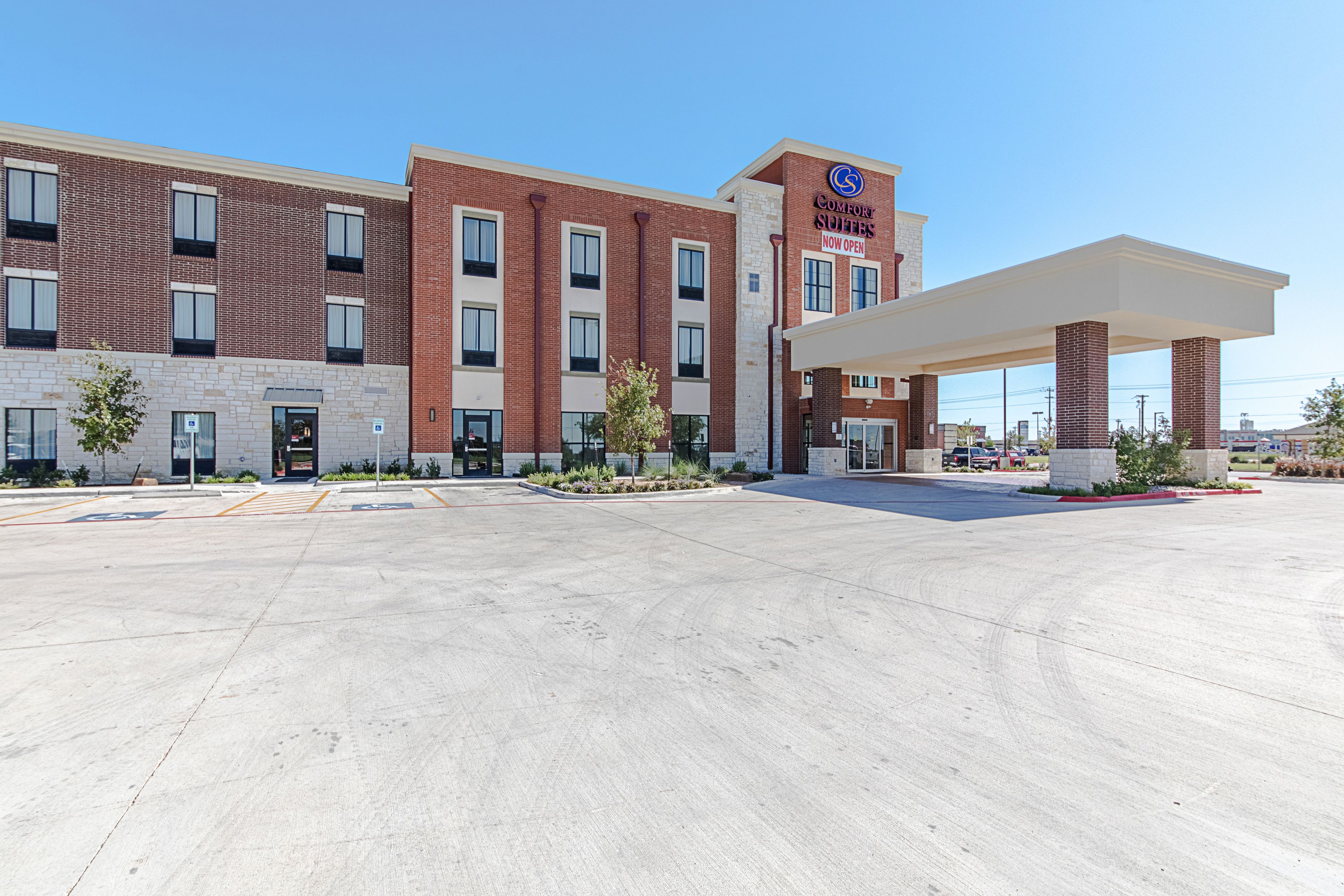 A hotel with a brick facade, a covered parking area, and a clear sky.