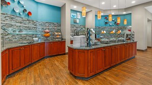 Una cocina moderna con una isla central, armarios de madera y una pared azul decorativa.