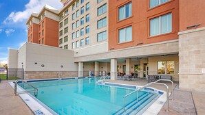 Un hotel con piscina, mobiliario exterior y un patio cubierto.