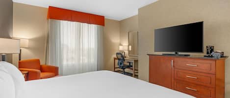 Ett hotellrum med en stor säng, ett skrivbord med en stol, en tv och en garderob.