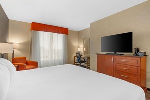 Een hotelkamer met een groot bed, een bureau met stoel, een televisie en een kledingkast.
