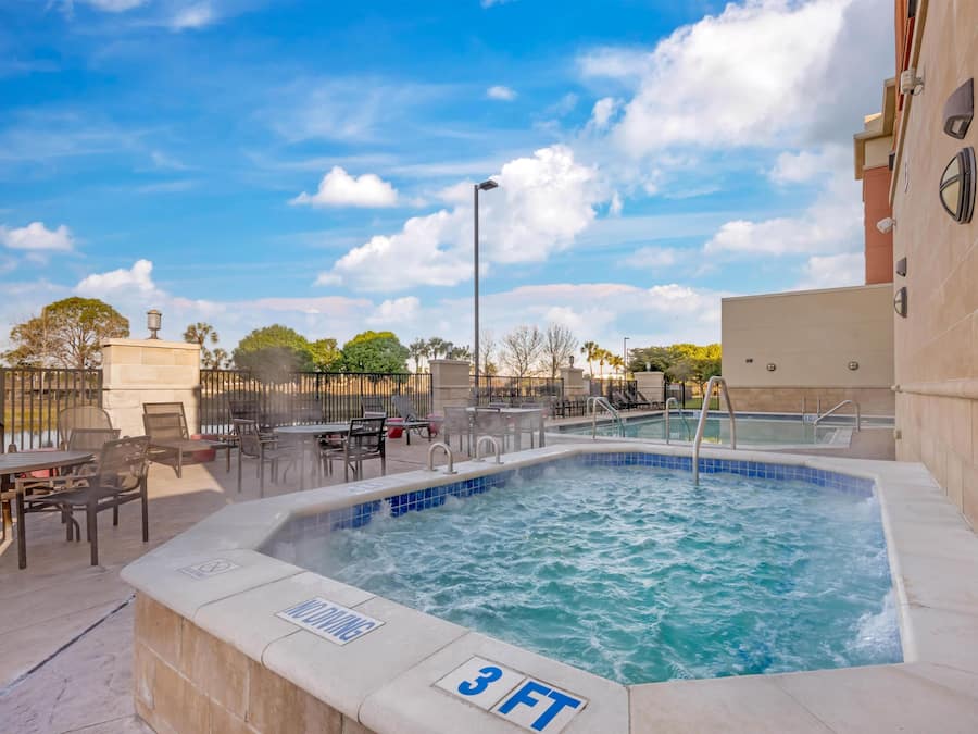 A swimming pool with a 3 FT depth marker, outdoor seating, and a clear sky.
