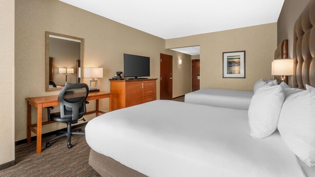 Een hotelkamer met een bed, een bureau met stoel, een televisie en een deur.