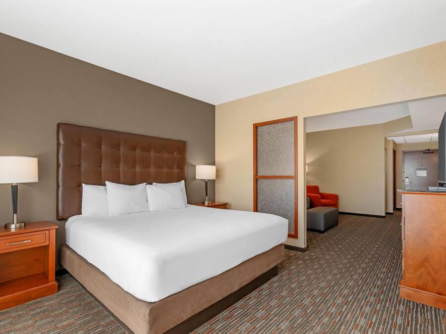Una habitación de hotel con una cama grande, dos mesitas de noche, un escritorio, una silla y una televisión.