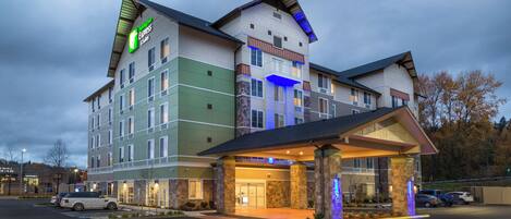 A multi-story hotel with a prominent entrance and a parking lot.