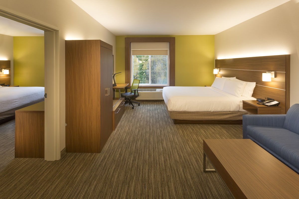 A hotel room with a bed, a sofa, a desk, and a chair.