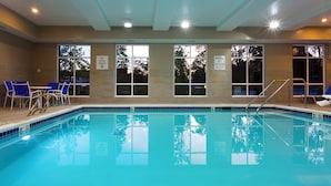 Une piscine intérieure à l’eau claire, dotée d’un plongeoir et de chaises longues.
