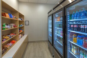 A refrigerated beverage display with various drinks and a snack shelf stocked with assorted items. - Holiday Inn Express & Suites Seattle South - Tukwila by IHG (Tukwila)