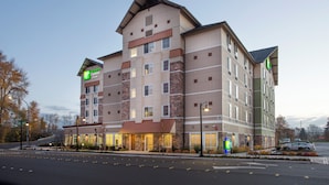 Un hôtel Holiday Inn Express à plusieurs étages, avec une façade en briques, de nombreuses fenêtres et une entrée bien éclairée.