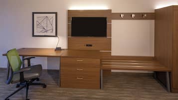 A modern office desk with a flat-screen monitor, a chair, and a framed abstract artwork on the wall.