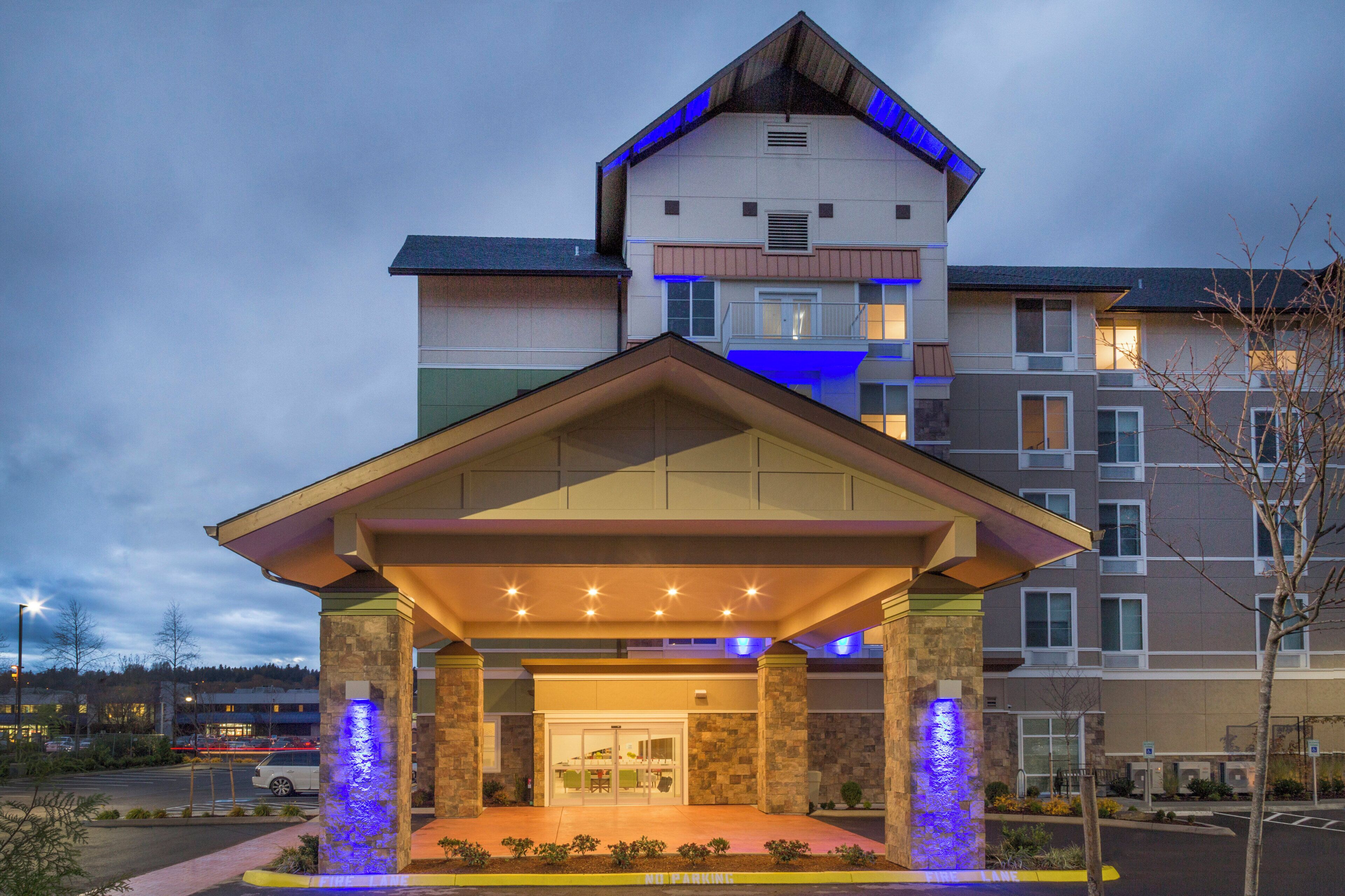 A hotel with a covered entrance, stone pillars, and a blue-lit facade.