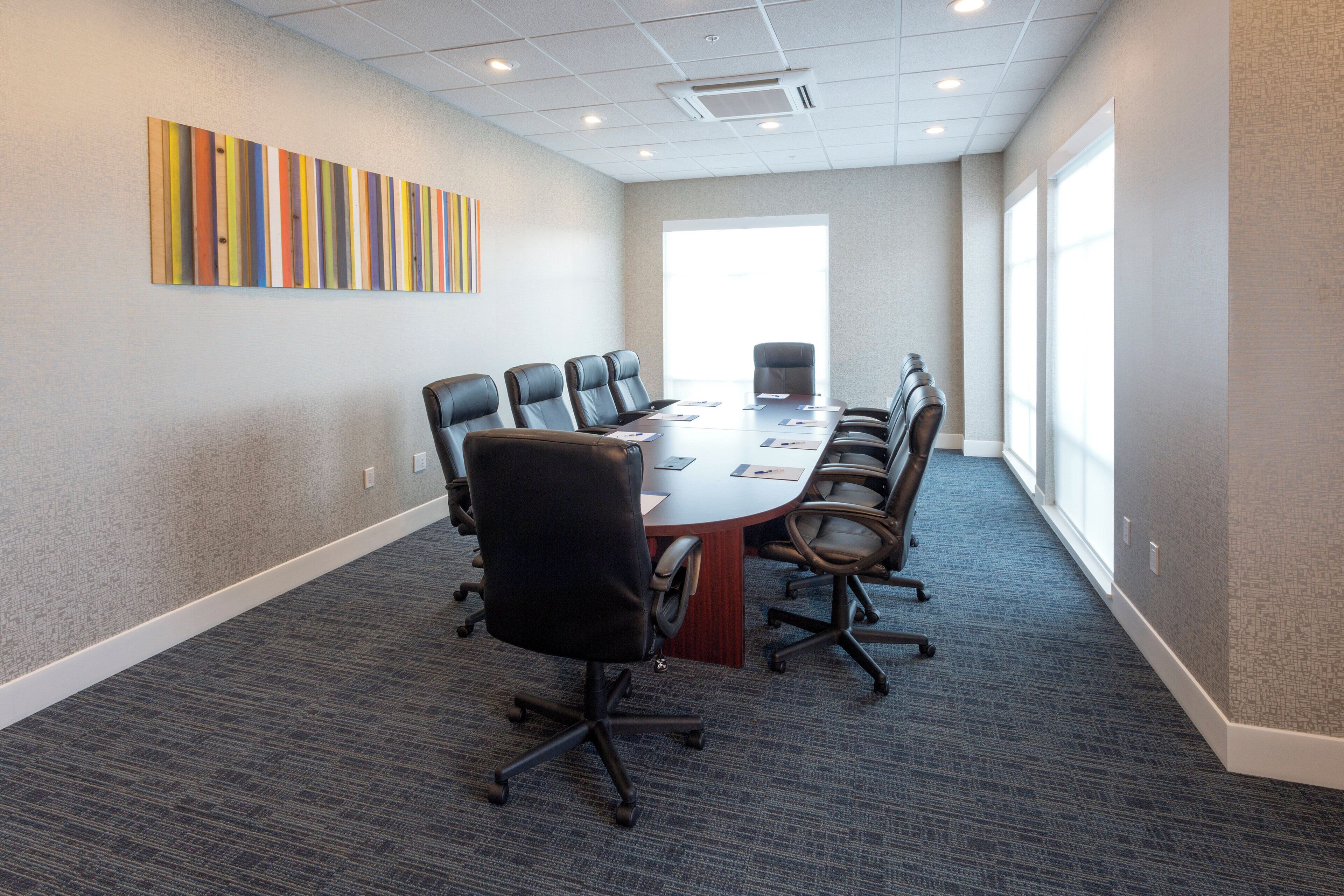 A conference room with a long table, multiple chairs, and a large window.