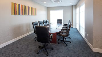 A conference room with a long table, multiple chairs, and a large window.
