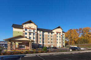 A multi-story hotel with a central entrance, parking lot, and a clear sky. - Holiday Inn Express & Suites Seattle South - Tukwila by IHG (Tukwila)