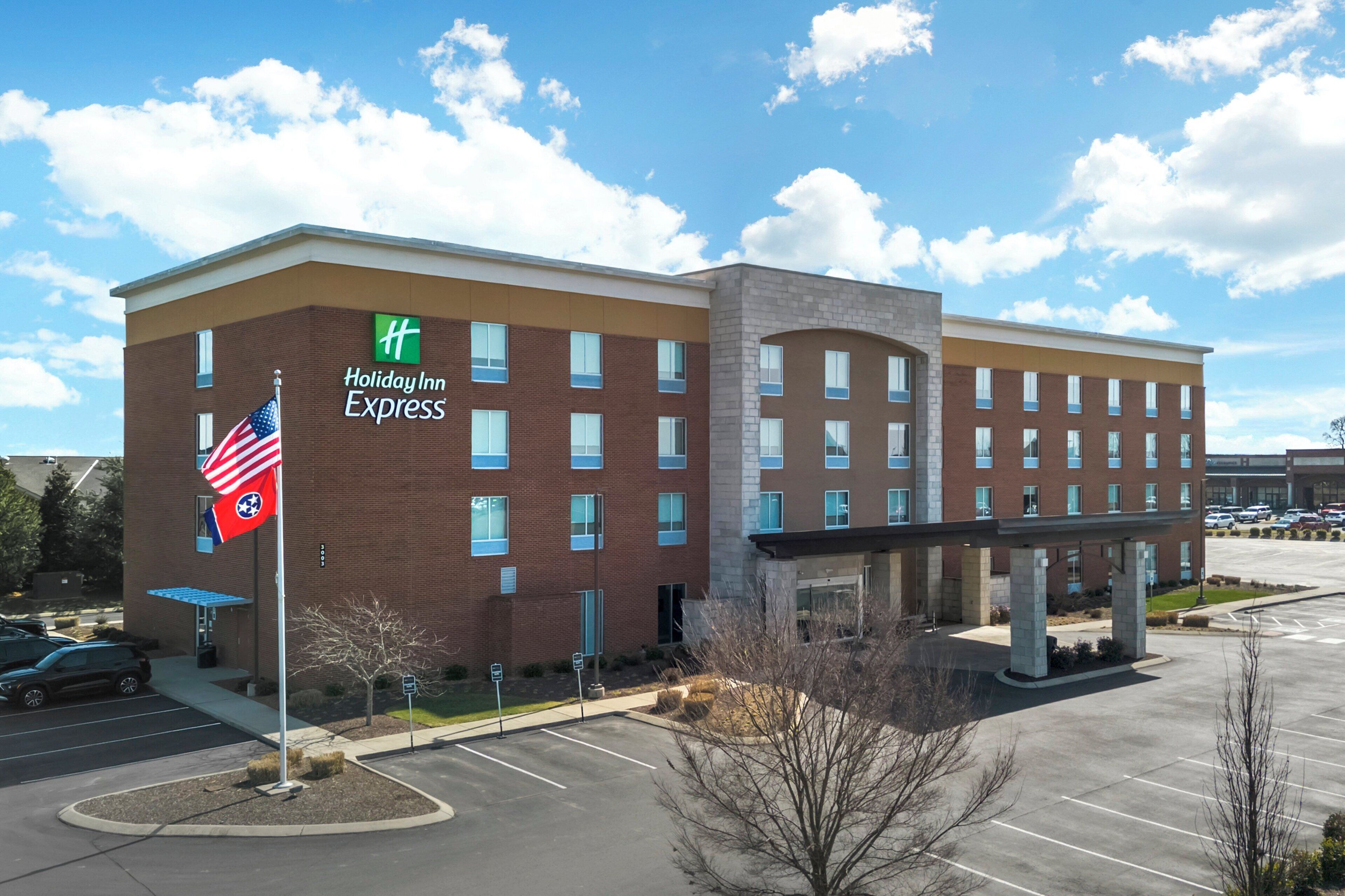 Edificio de Holiday Inn Express con estacionamiento y una bandera.