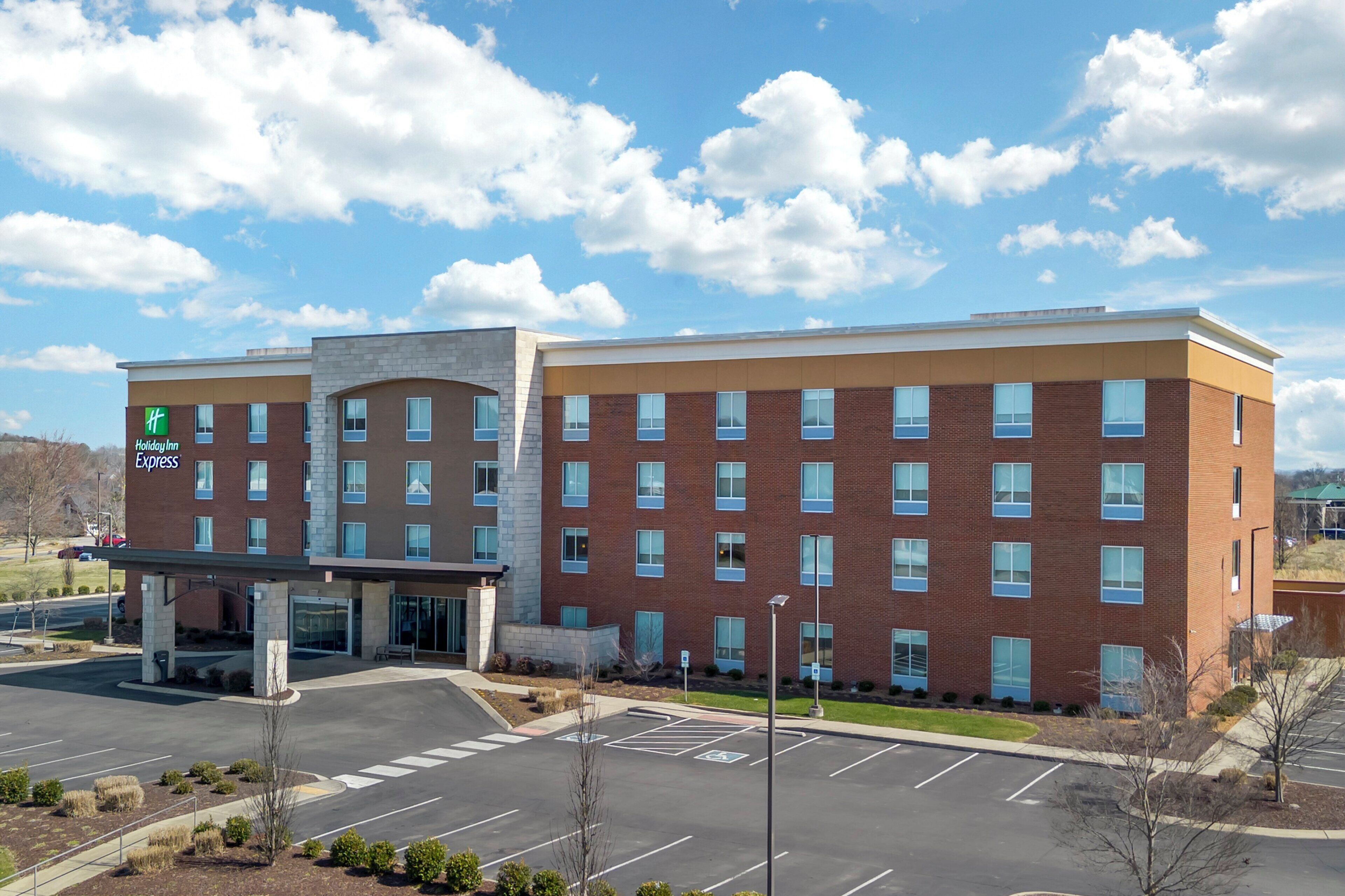 A hotel with a brick facade, multiple windows, and a parking lot.